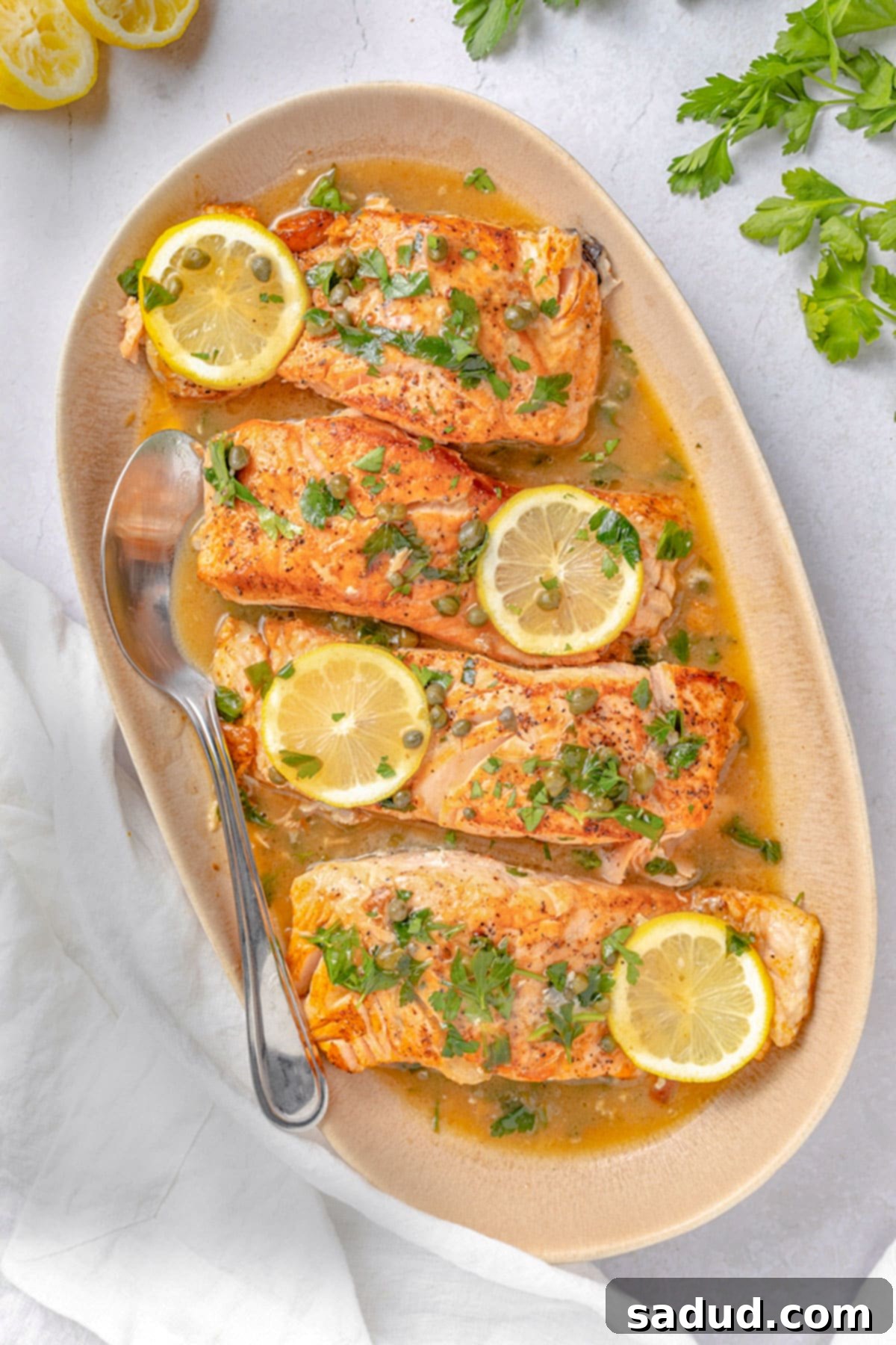 4 salmon piccata fillets on an oval serving platter.