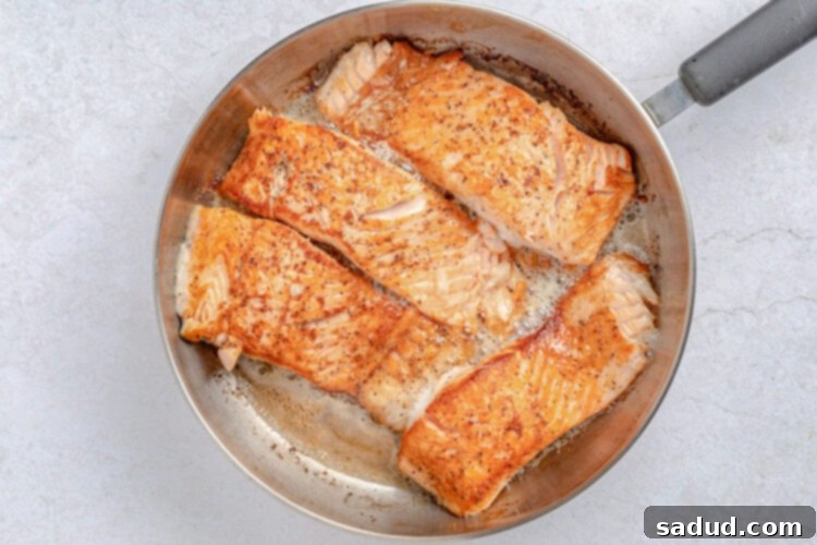 Salmon slices in a large skillet with melted butter.