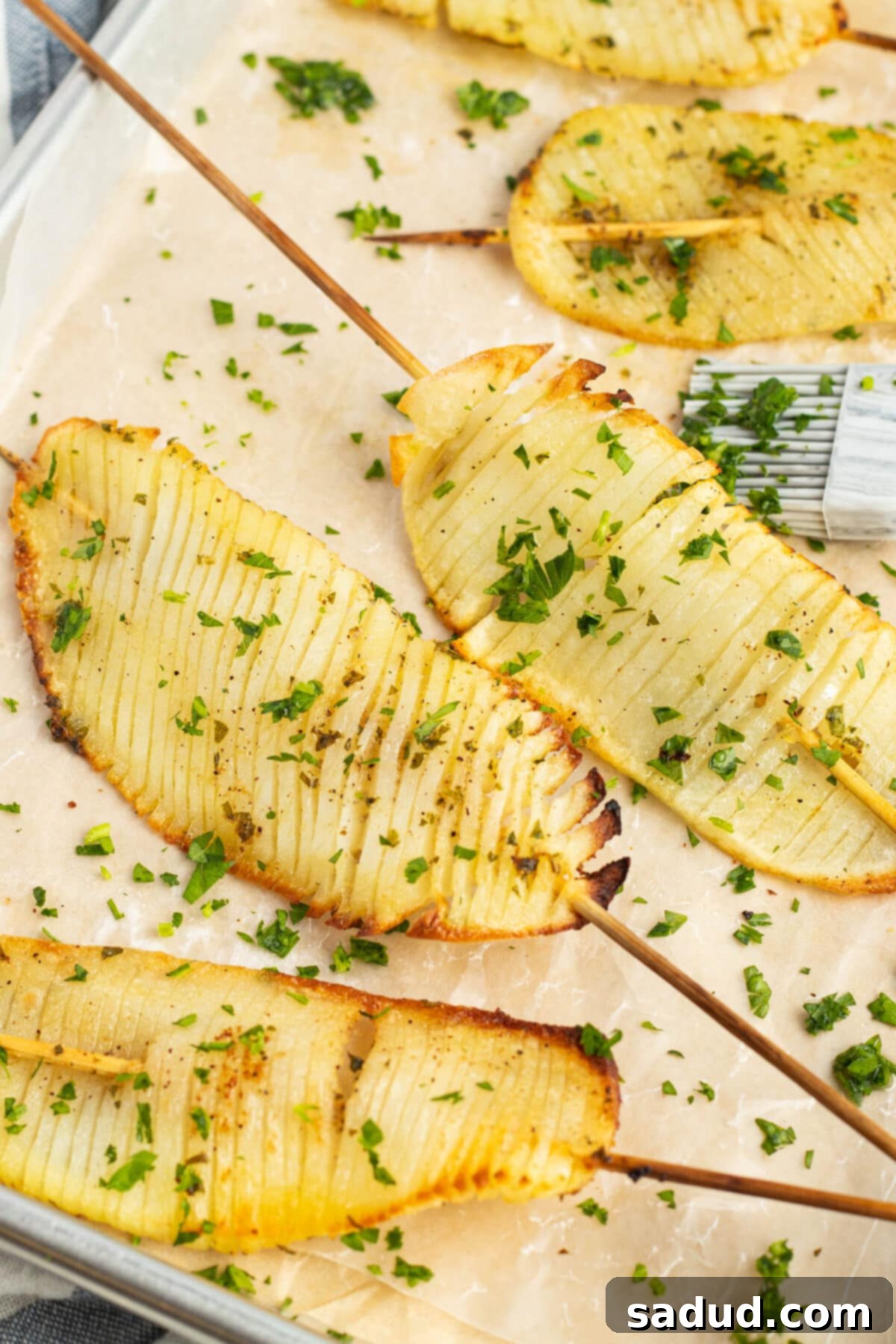 Golden brown crispy accordion potatoes on skewers, beautifully arranged on parchment paper, ready to be served as an impressive side dish or appetizer.