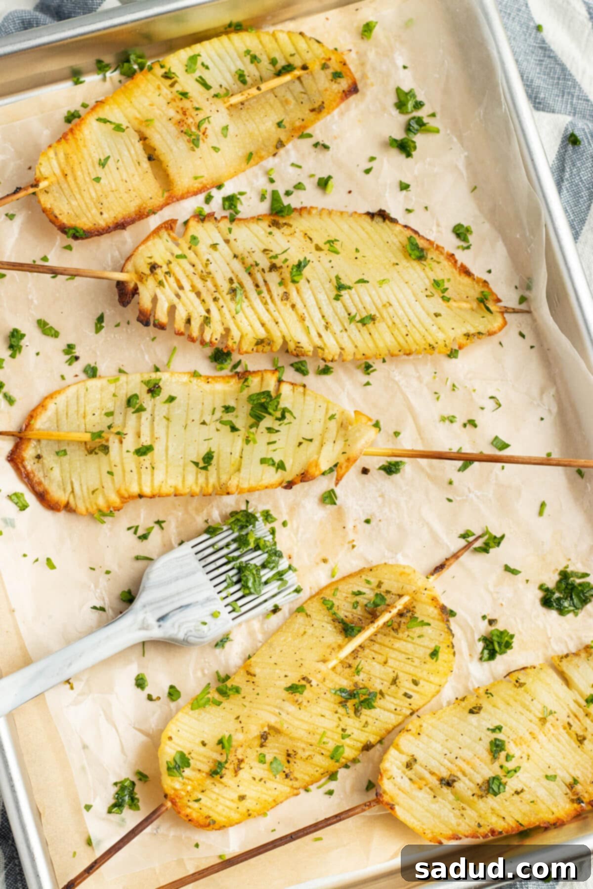 Close-up of golden brown crispy accordion potatoes on skewers, garnished with fresh parsley, ready to be served.