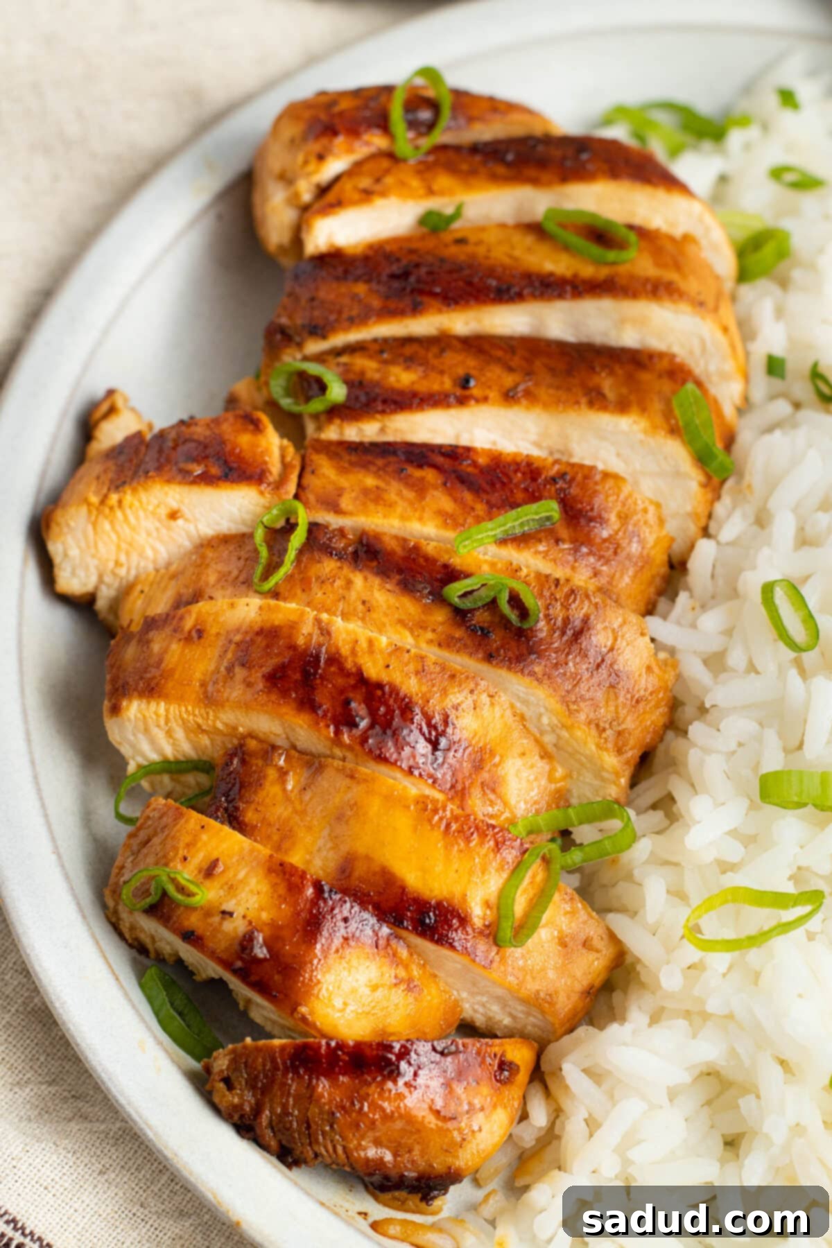 Top-down view of grilled chicken adobo, sliced and arranged on a platter with rice.