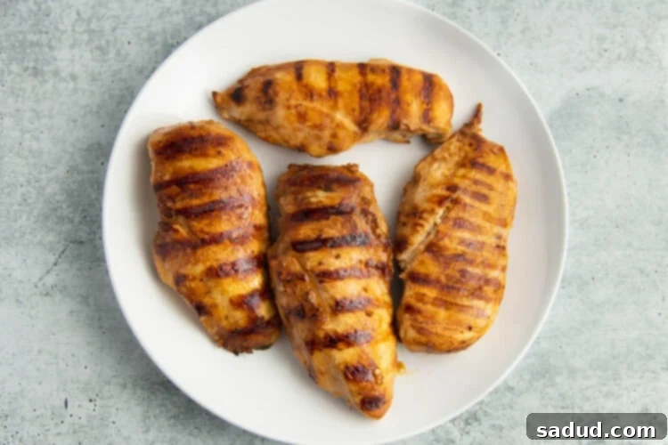 Grilled adobo chicken on a large round white plate.