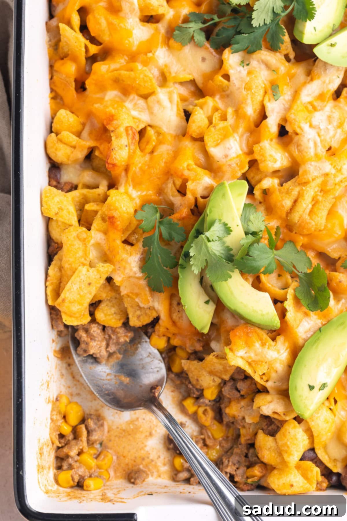 Loaded Taco Casserole 2 Walking taco casserole in a rectangular white casserole dish. A scoop is missing.