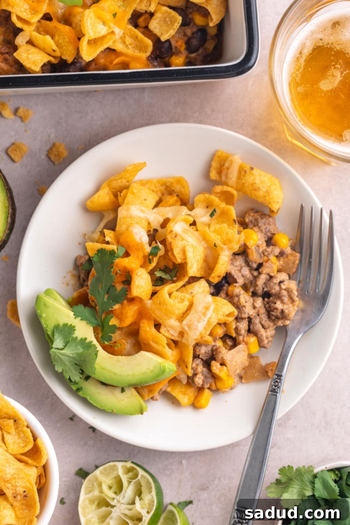 Loaded Taco Casserole 3 A serving of walking taco casserole on a round white plate with a silver fork.
