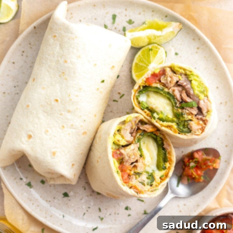 Overhead view of a chile relleno burrito cut in half and stood up on a plate, next to a whole burrito.