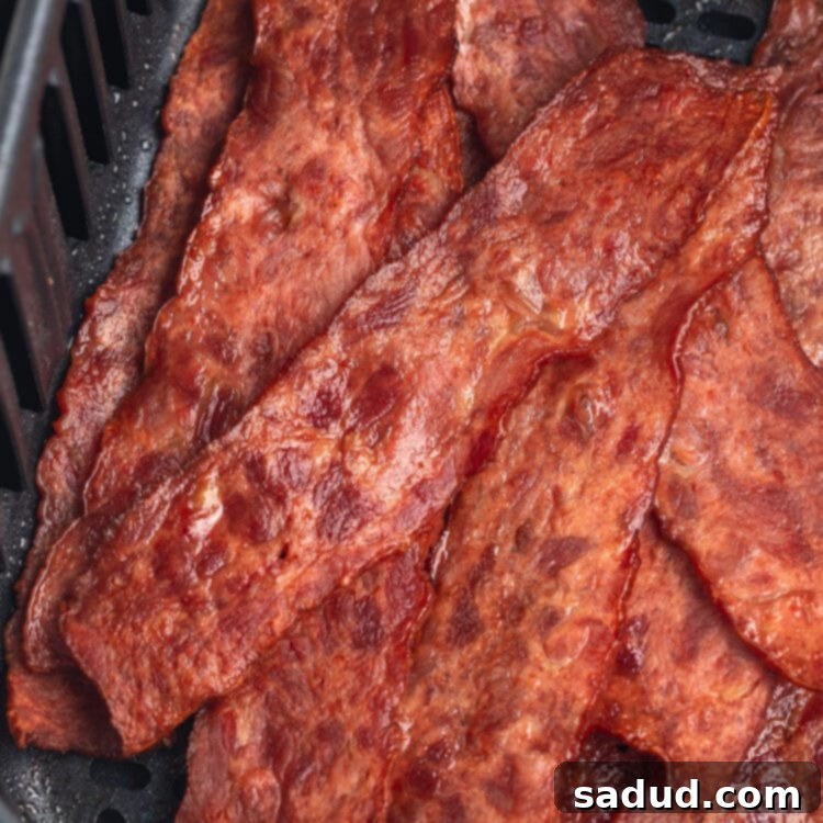 Top-down view of strips of crispy turkey bacon in an air fryer basket.