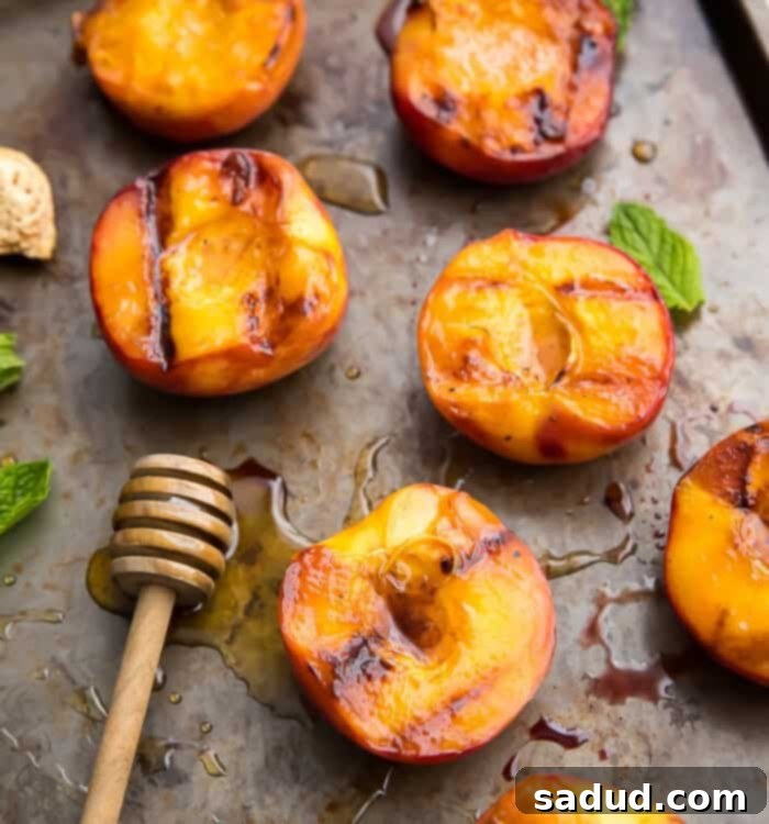 Grilled peaches on a baking sheet, glistening with honey and cinnamon