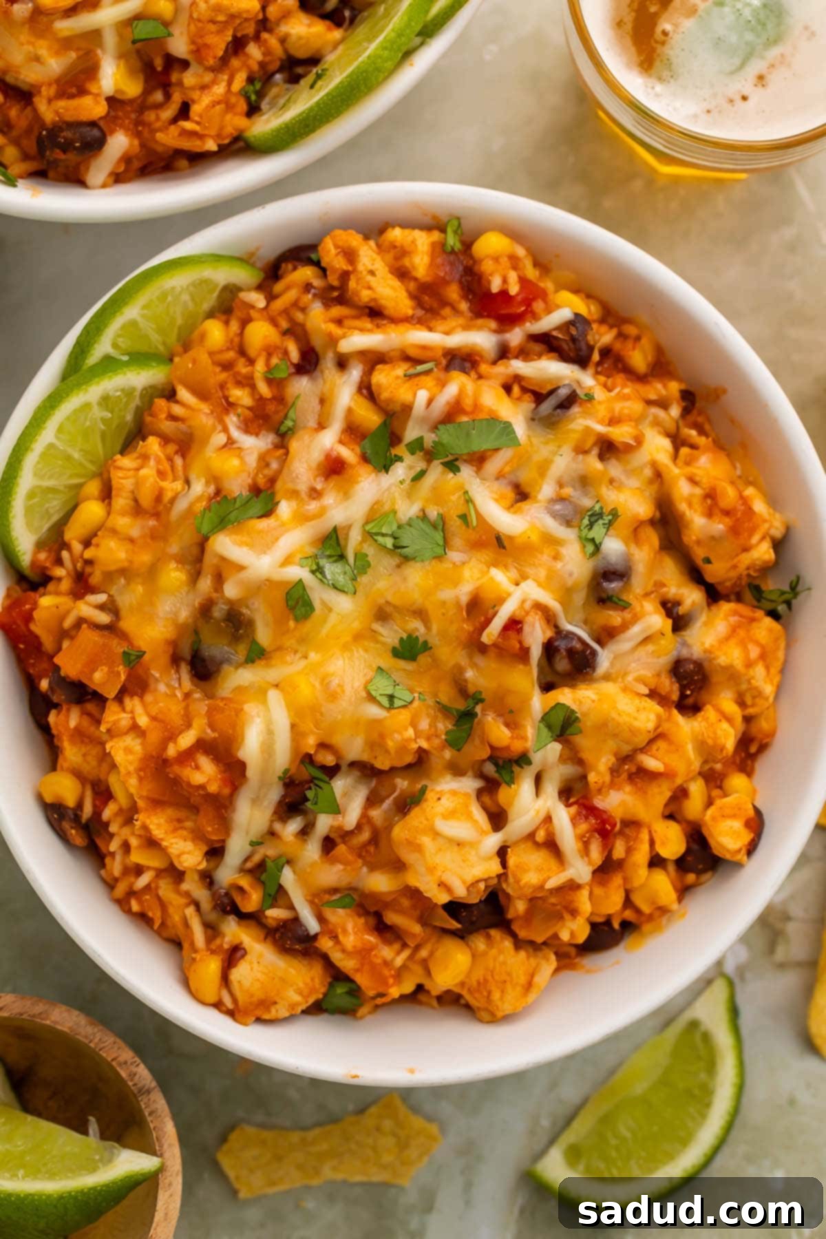 Instant Pot Chicken and Bean Fiesta Bowls 2 Overhead photo of a chicken burrito bowl with rice, cooked in the Instant Pot, on a table surrounded by lime wedges and a glass of white wine.