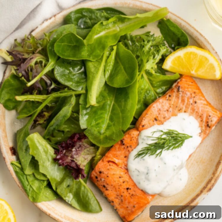 Perfect 10-Minute Air Fryer Salmon 4 A perfectly cooked salmon fillet, served with a fresh green salad and a dollop of creamy dill sauce, showcasing the quick and easy air fryer method.
