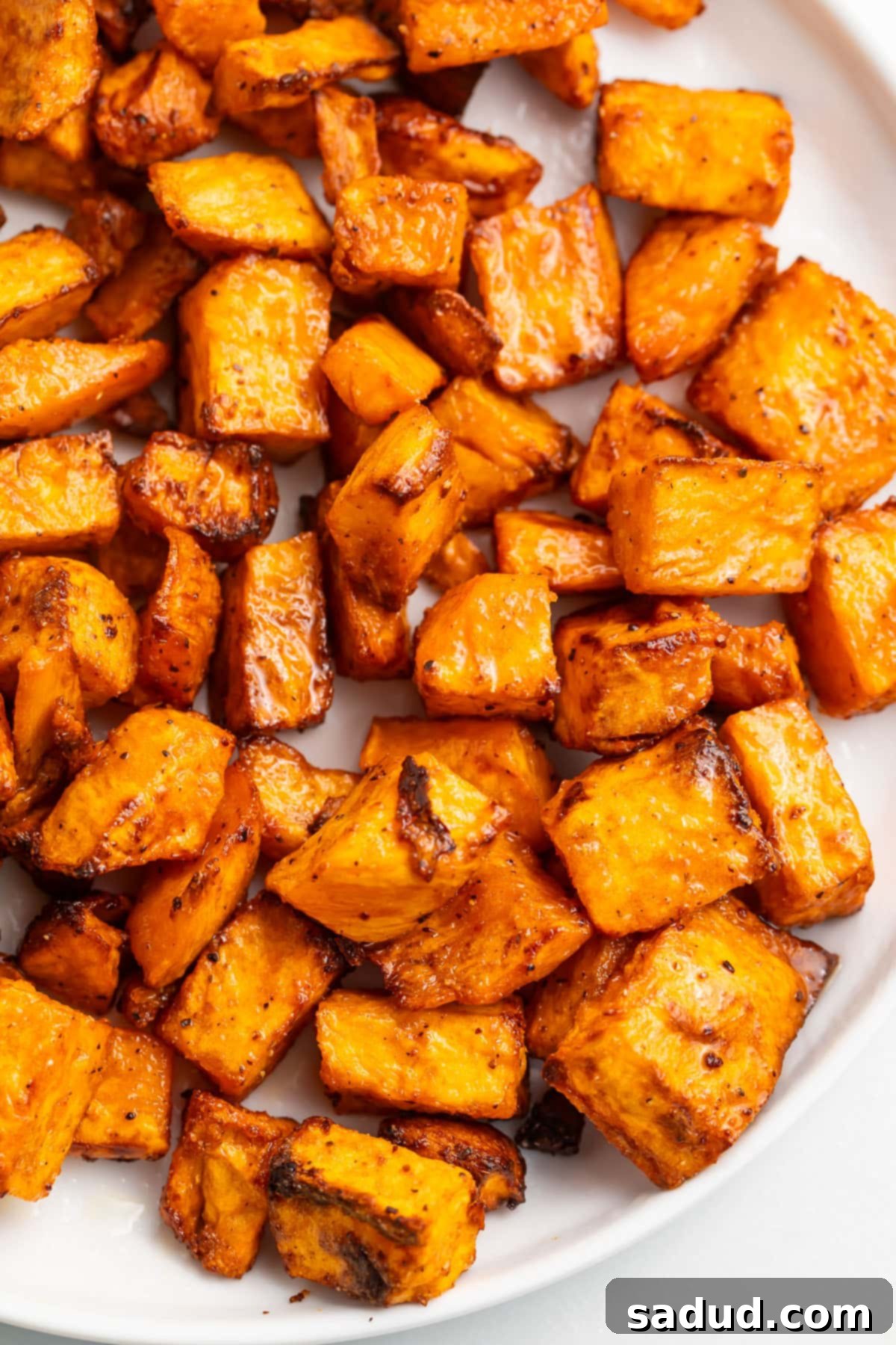 Sweet potato cubes, cooked in the air fryer, shown on a white plate.