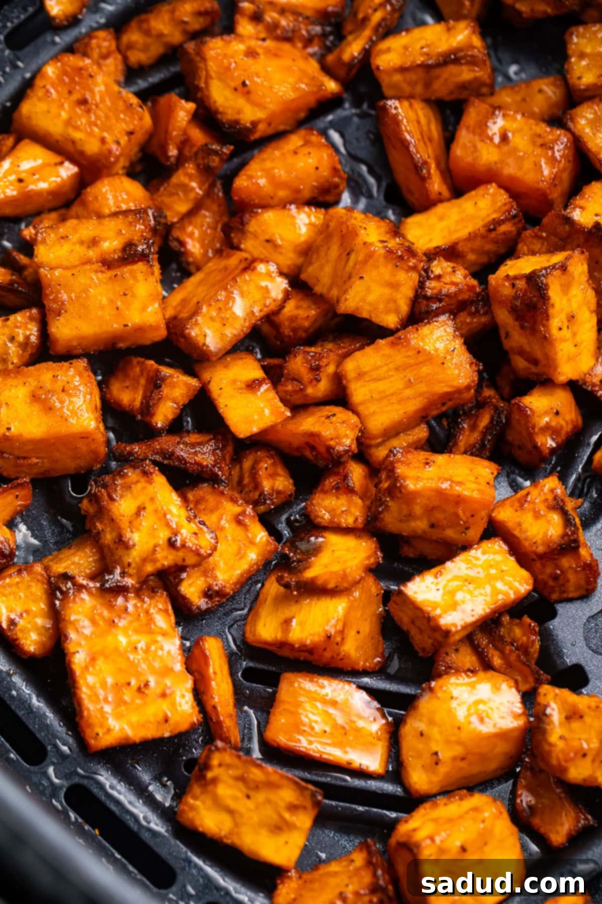 Sweet potato cubes, cooked until brown and crisp, in an air fryer basket.