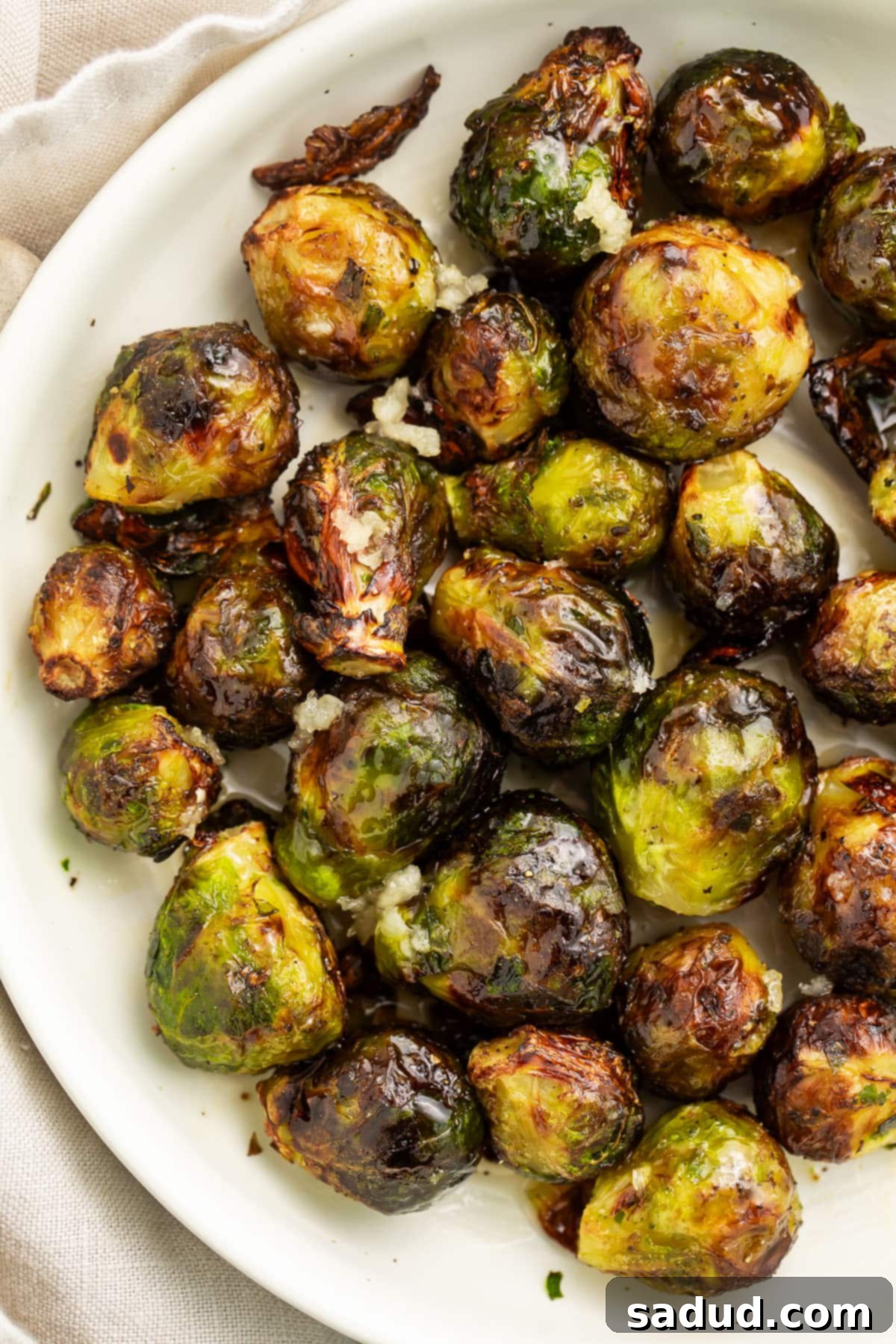 Air fryer frozen brussels sprouts on a large white plate, perfectly golden and crispy.