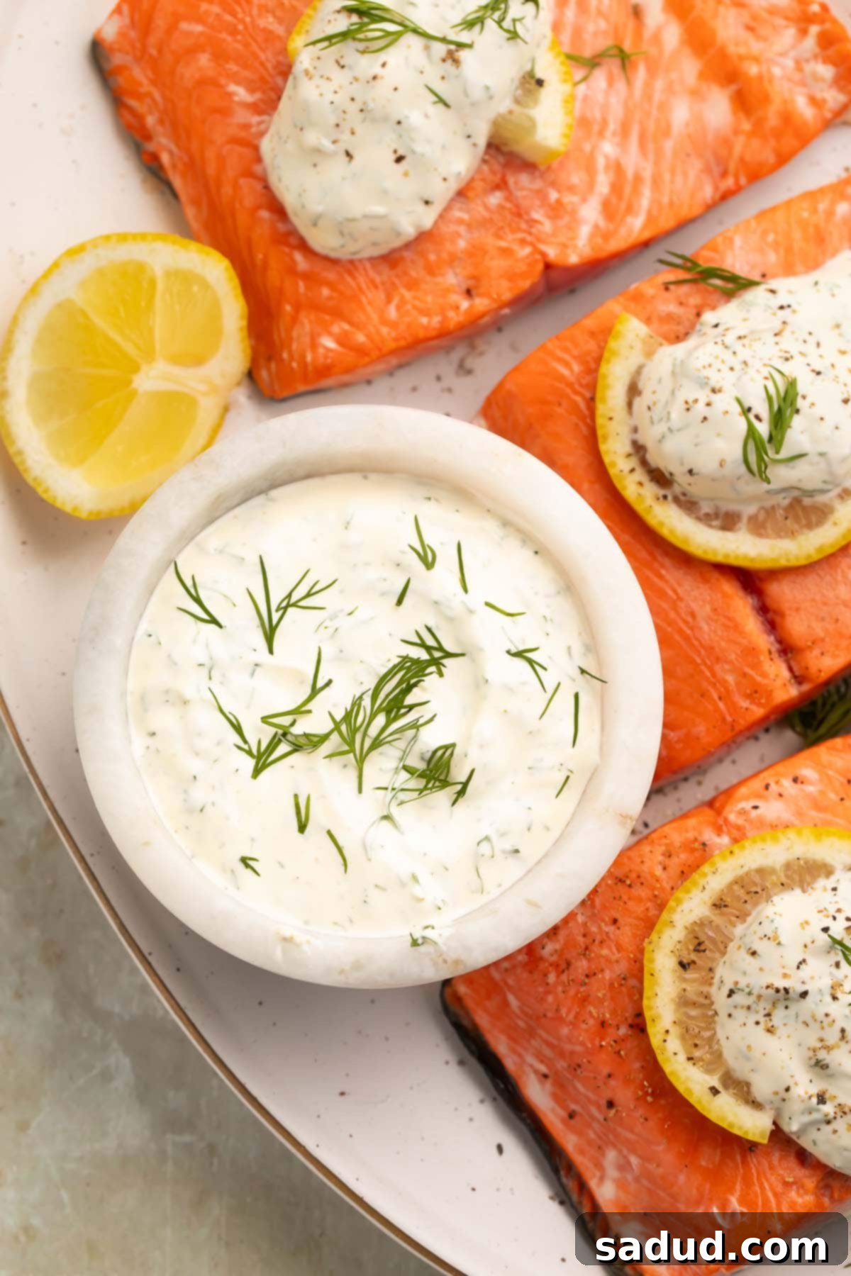 A small marble bowl holding creamy dill sauce garnished with a sprig of fresh dill.