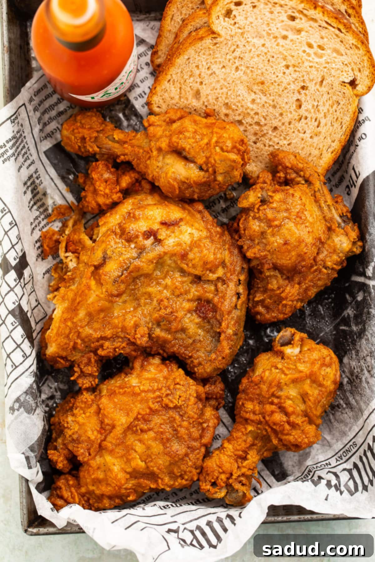 Reheat Fried Chicken to Crispy Perfection in Your Air Fryer 3 Crispy fried chicken, reheated in the air fryer, in a pan lined with newspaper.