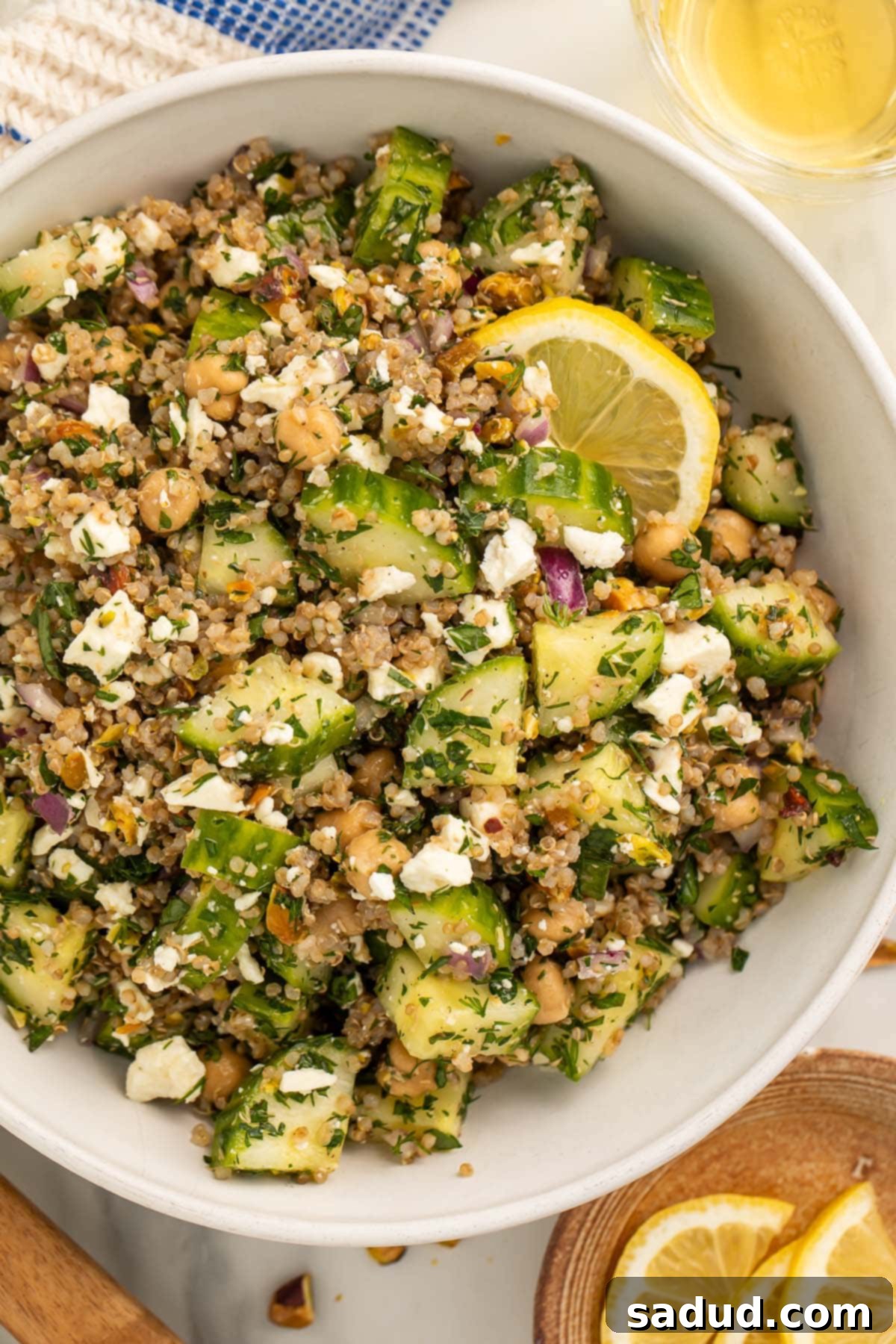 Jennifer Aniston's Viral Salad: The Internet's Favorite Recipe 2 The viral Jennifer Aniston salad (quinoa, chickpeas, cucumber, pistachios, feta, and herbs) in a large white bowl with slices of fresh lemon.