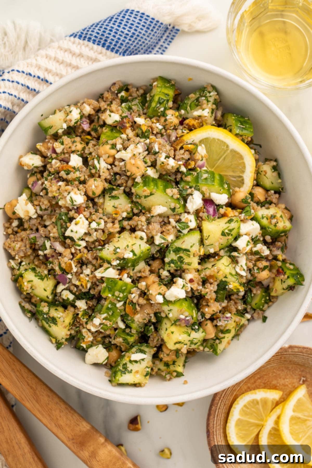 Jennifer Aniston's Viral Salad: The Internet's Favorite Recipe 3 The viral Jennifer Aniston salad (quinoa, chickpeas, cucumber, pistachios, feta, and herbs) in a large white bowl with slices of fresh lemon.