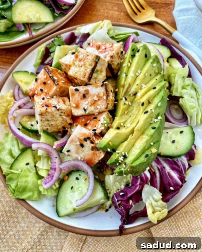 A vibrant salad topped with crispy buffalo tofu and drizzled with creamy tahini ranch dressing.