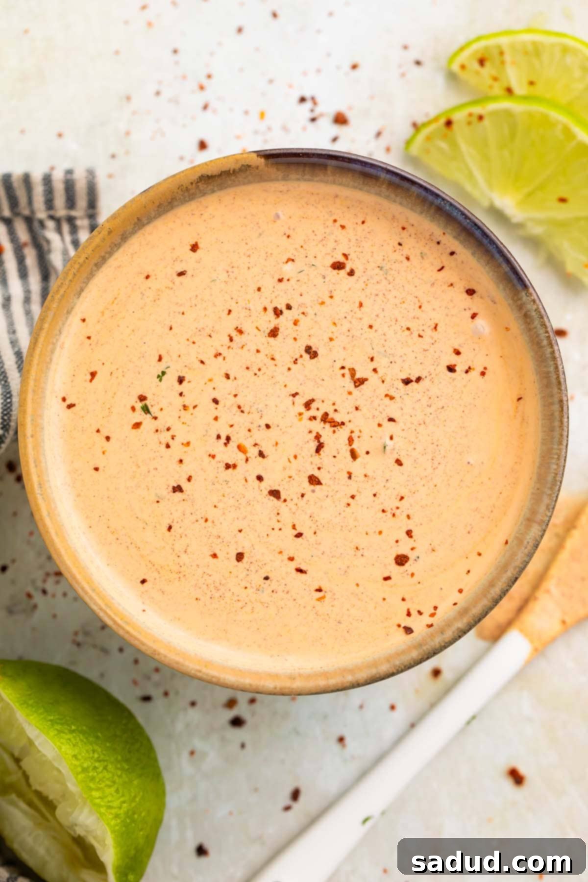 An overhead shot showcasing the beautiful peach-colored Southwest salad dressing, elegantly garnished with a light dusting of smoked paprika, served in a tasteful medium bowl.