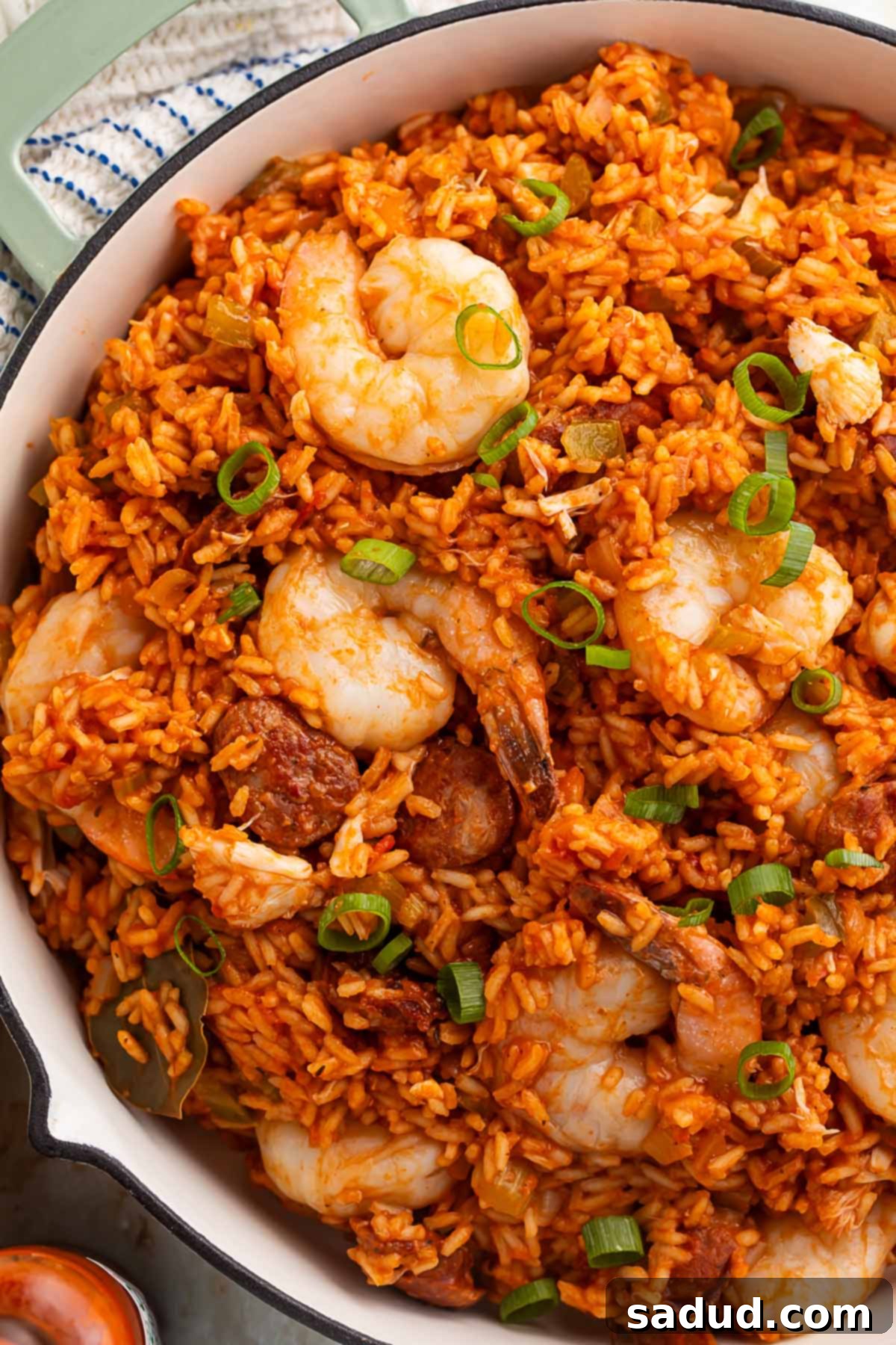 Spicy Cajun Seafood Medley 2 A generously sized Dutch oven filled with a rich, vibrant seafood jambalaya, featuring plump shrimp, tender rice, and smoky Andouille sausage, ready to be served.