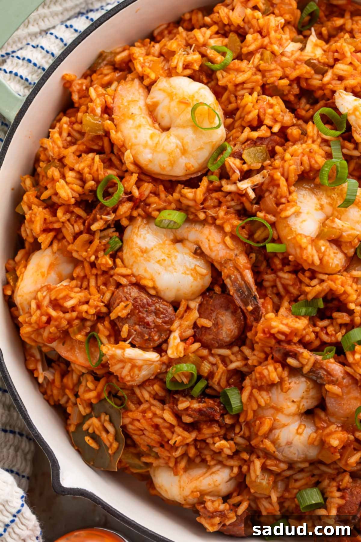 Spicy Cajun Seafood Medley 4 A spoon scooping a generous portion of Louisiana seafood jambalaya from a large pot, highlighting the tender shrimp, flavorful rice, and savory Andouille sausage.