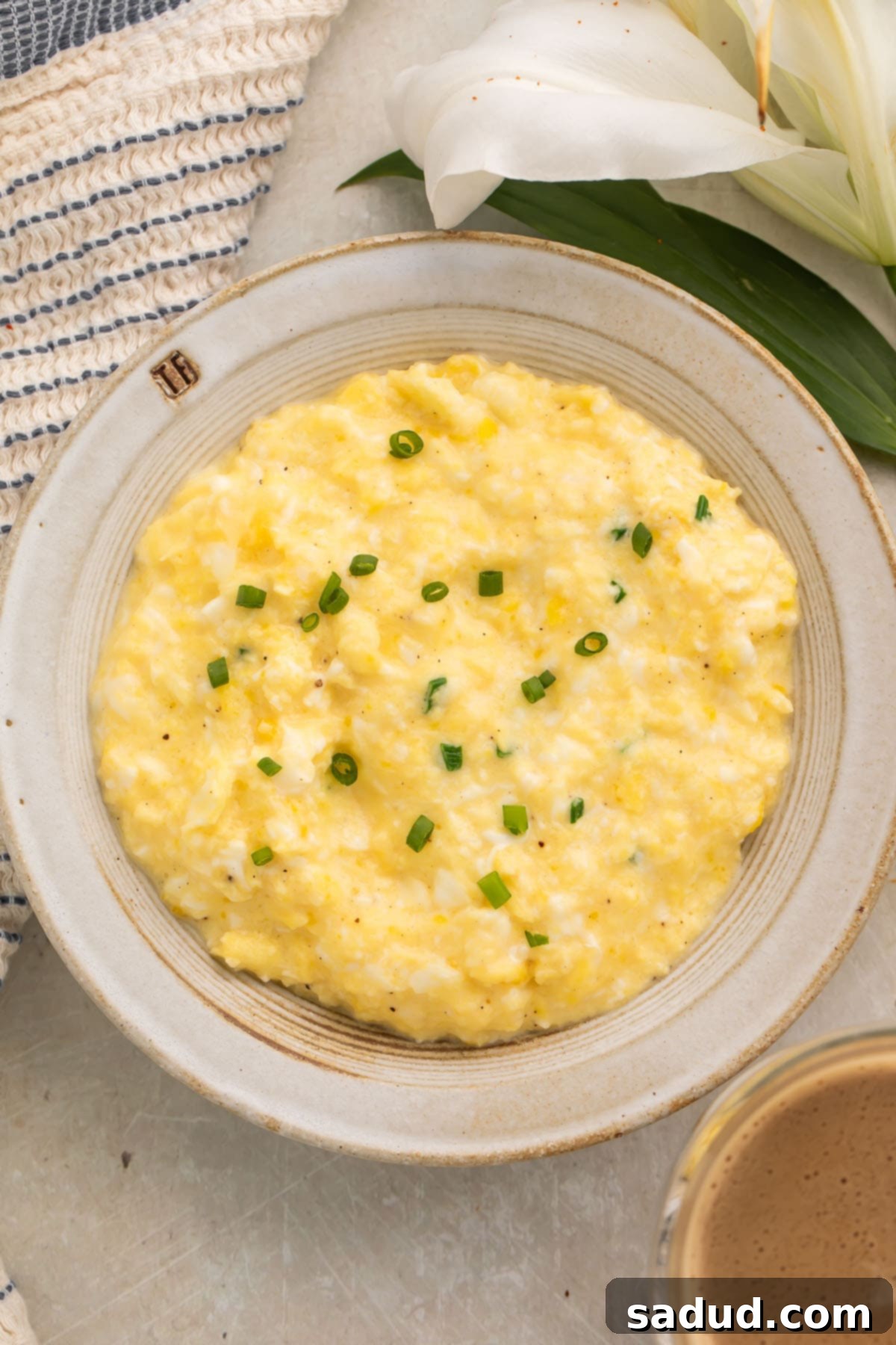 A close-up shot of fluffy, creamy scrambled cottage cheese eggs in a large bowl, garnished with freshly chopped green onions, showcasing their appealing texture.
