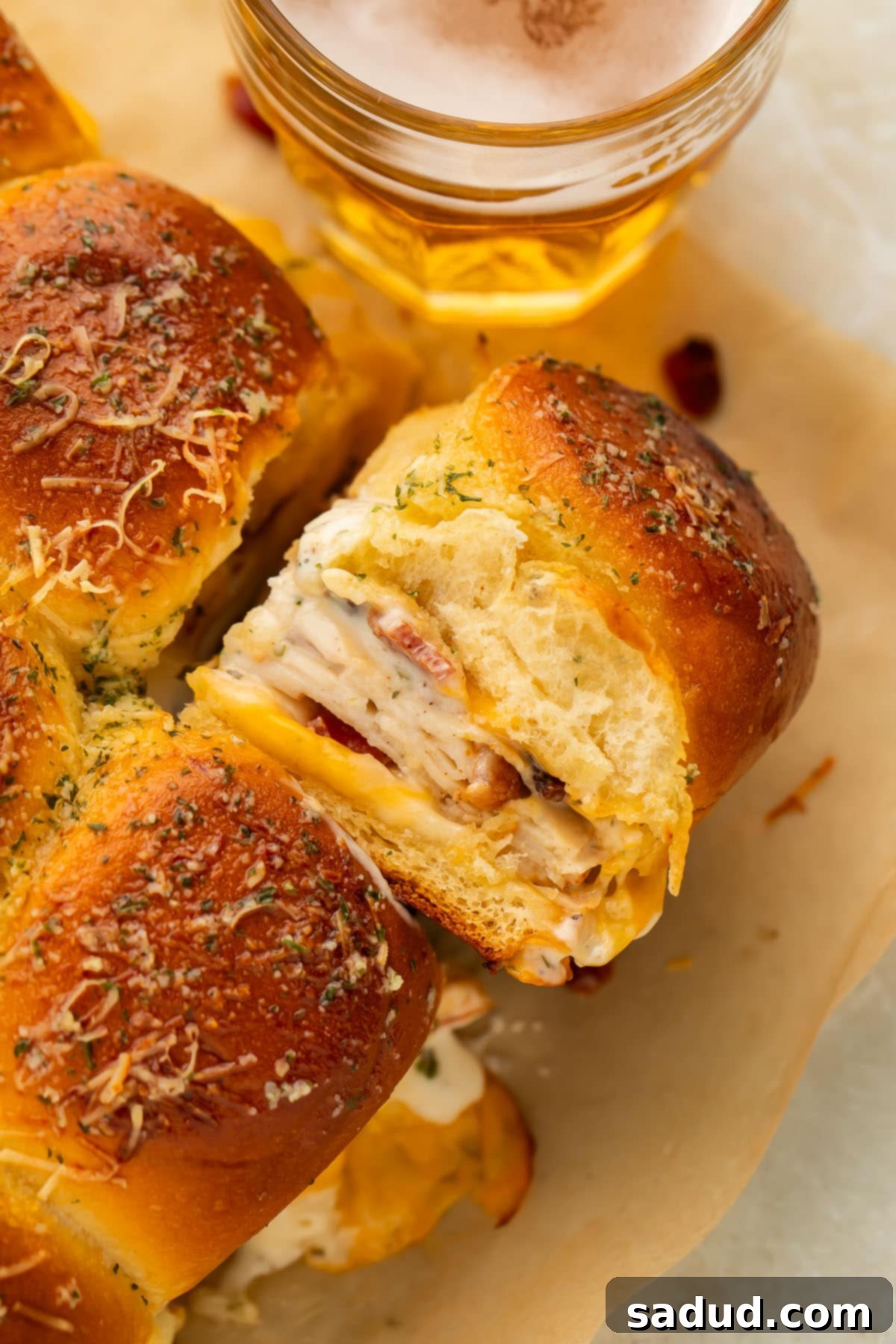A chicken bacon ranch slider turned on its side to show the layers of deli chicken, bacon, cheese, and ranch dressing.