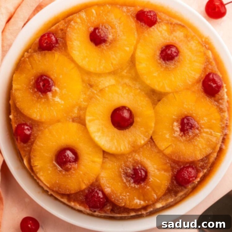A whole, round, gluten-free pineapple upside down cake, topped with pineapple rings and cherries, ready to be sliced.