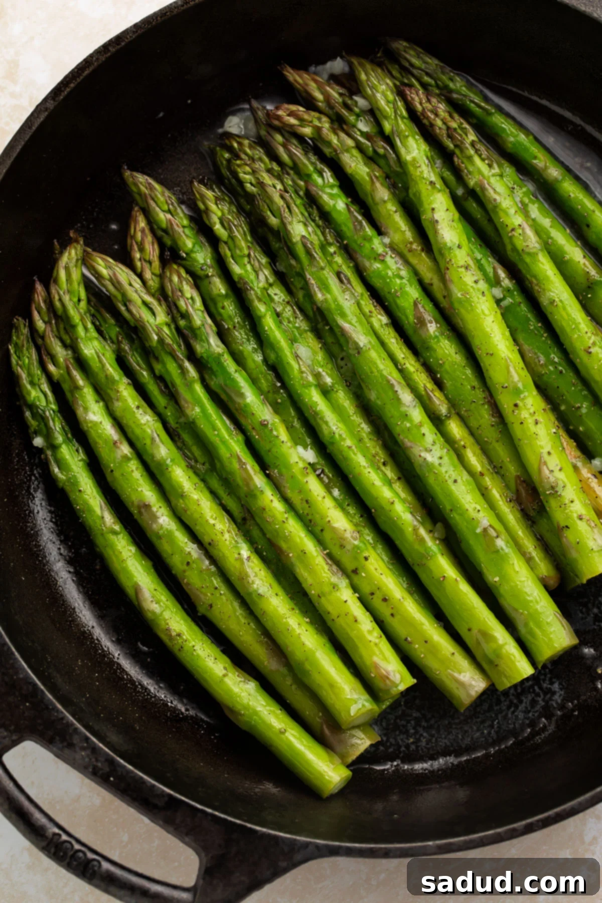 Stalks of perfectly smoked asparagus nestled in a large cast-iron skillet, ready to be served.