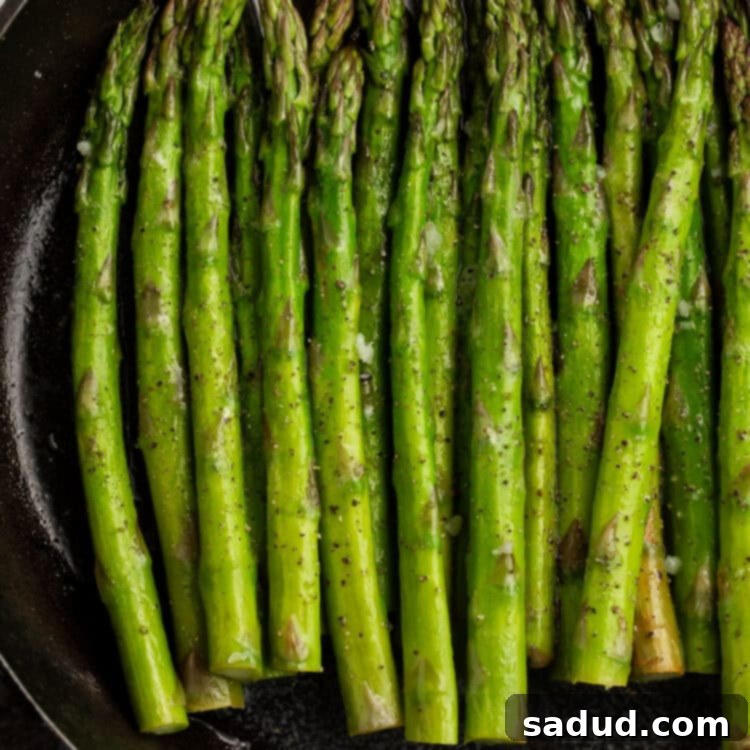 Beautifully smoked asparagus spears in a cast-iron skillet, topped with fresh parsley.