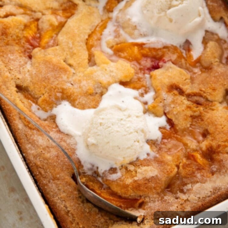 Overhead photo of a rectangular baking dish holding a gluten free peach cobbler topped with scoops of vanilla ice cream.