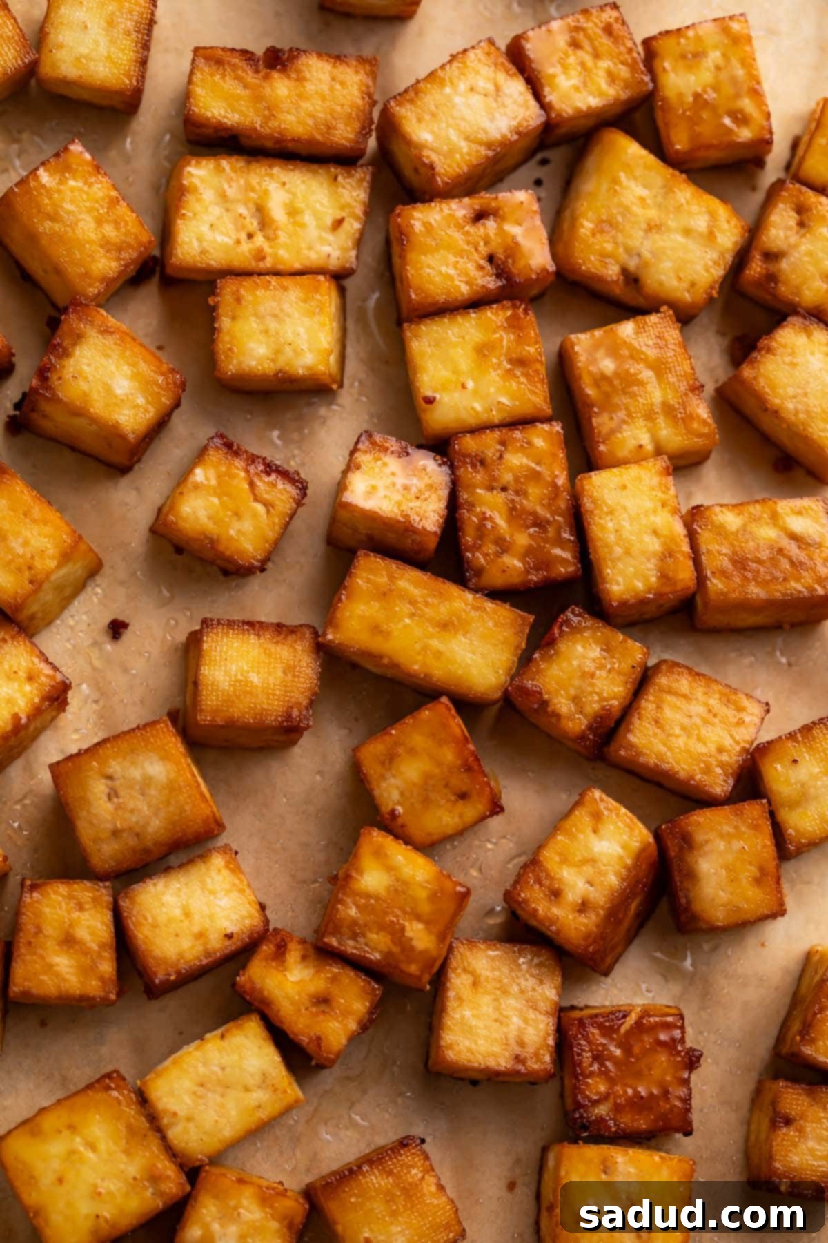Crispy golden-brown squares of smoked tofu, perfectly arranged on parchment paper, ready to be served.