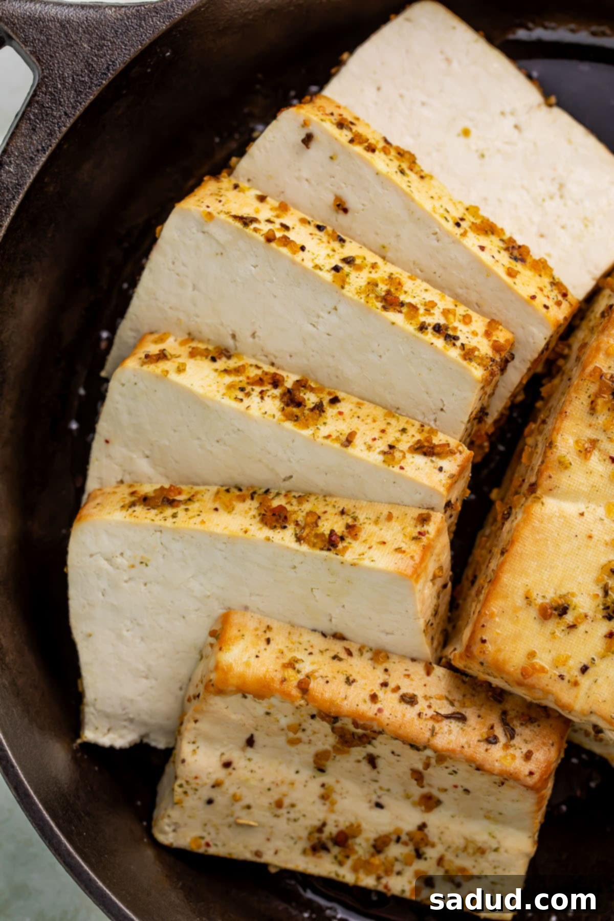 Thick squares of golden smoked tofu, beautifully arranged in a rustic cast iron skillet, ready to be enjoyed.
