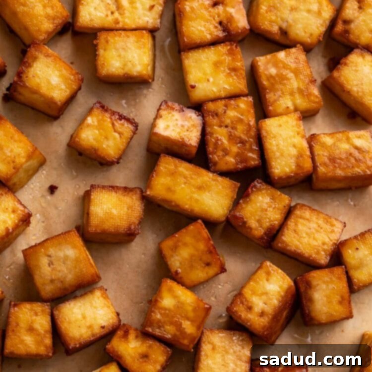 Squares of crispy smoked tofu, a delicious plant-based protein, arranged on a sheet of parchment paper.
