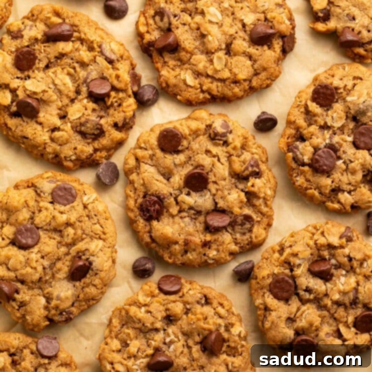 A stack of perfectly baked vegan oatmeal chocolate chip cookies with melted chocolate, set against a rustic background.