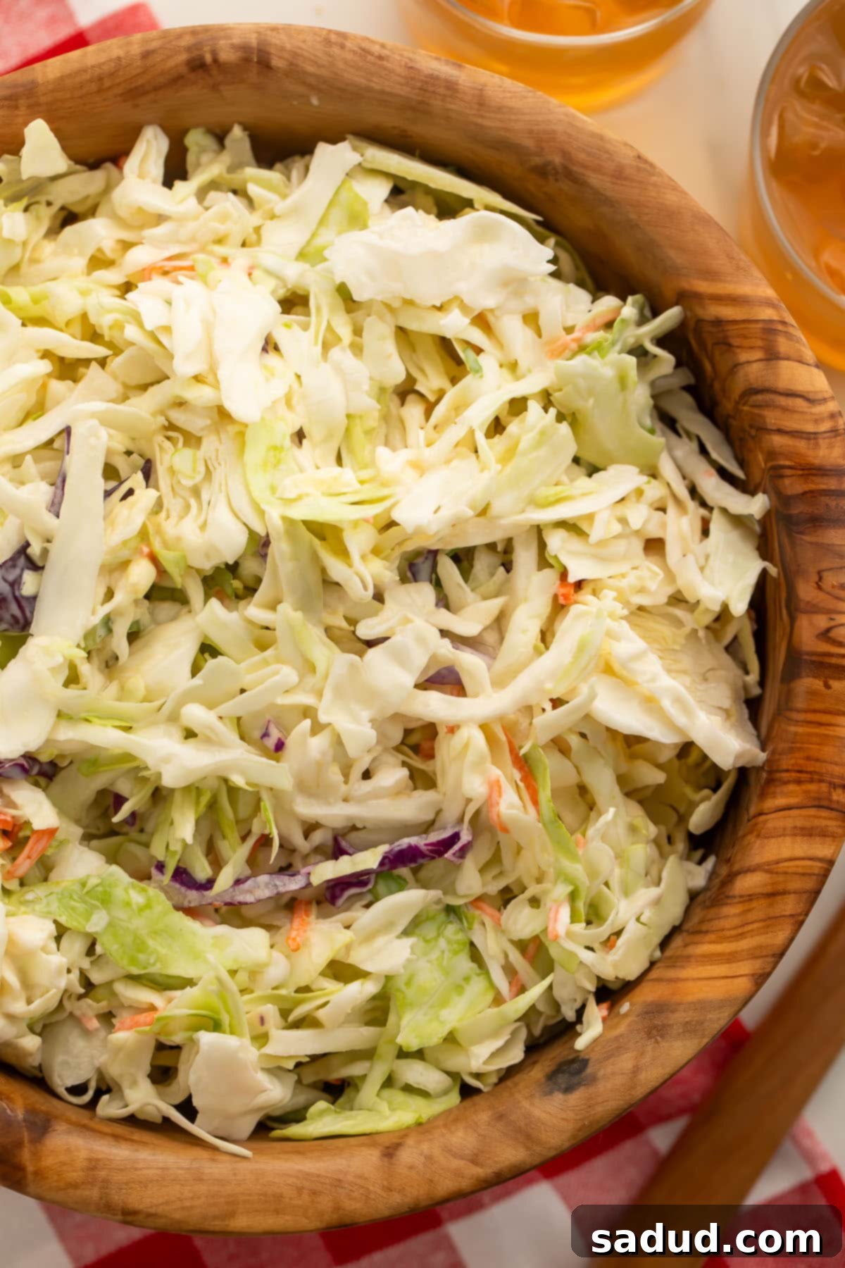 Close-up of a wooden bowl filled with freshly made vegan coleslaw, showcasing its creamy texture and crisp shredded vegetables.