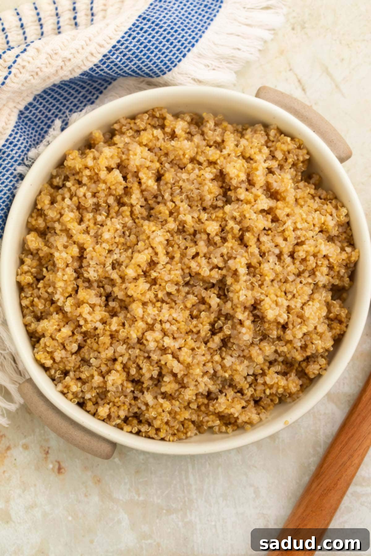 A bowl of rich, fluffy Instant Pot quinoa on a counter with a blue and white striped kitchen towel, showcasing its perfect texture.