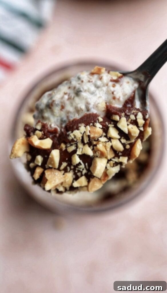 A spoonful of creamy Snickers chia pudding topped with chopped peanuts, ready to eat.