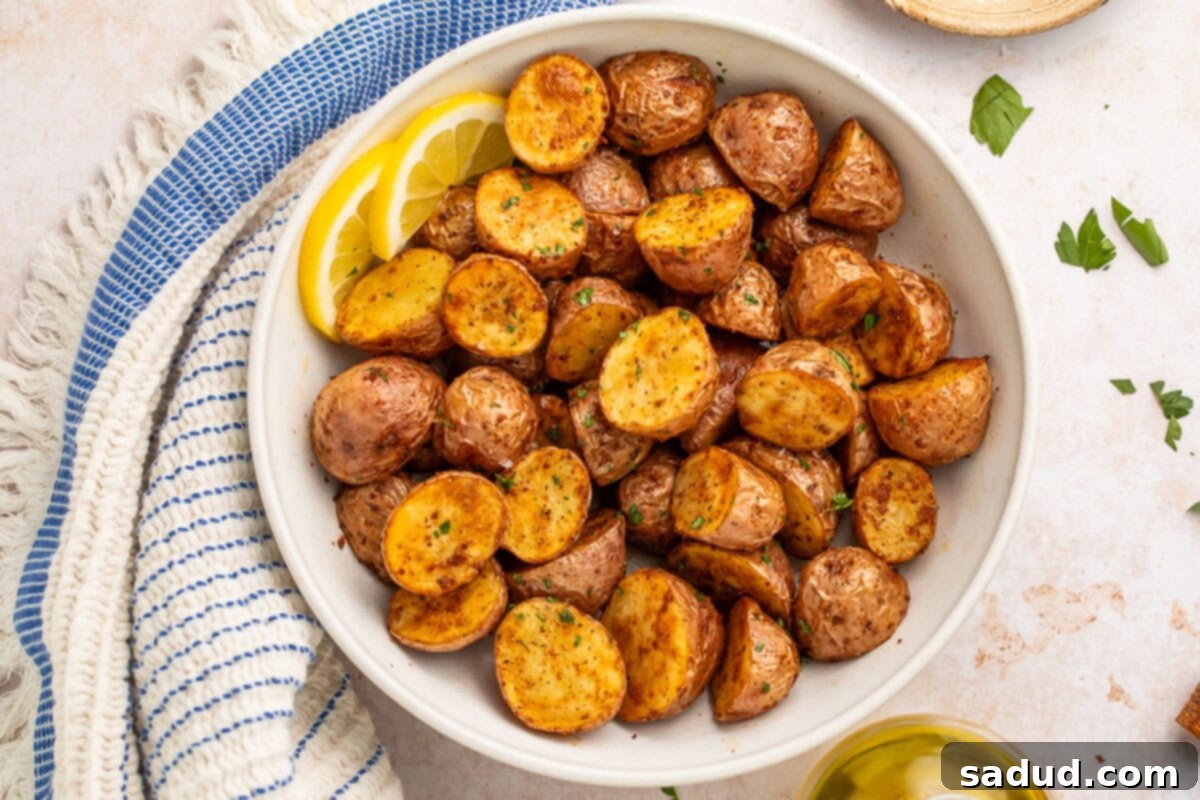 Quick and Crispy Air Fryer Red Potatoes 3 A bowl of air fryer red potatoes with 2 lemon slices next to a blue striped kitchen towel.