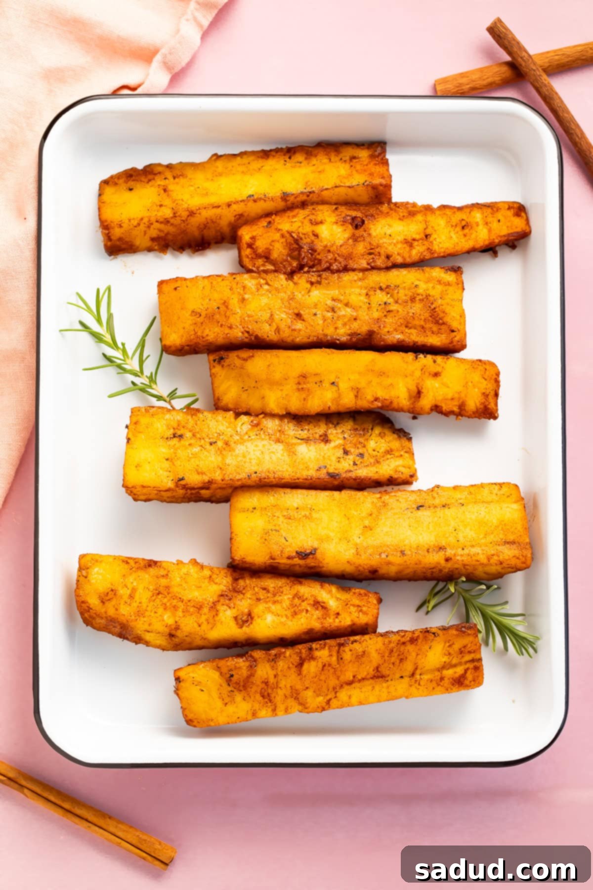 Smoked Pineapple 3 Smoked pineapple spears arranged in a staggered row in a white rectangular baking dish.