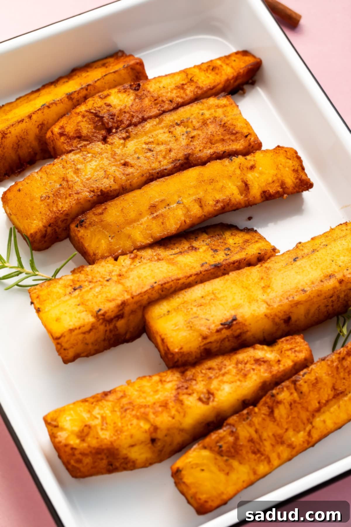 Smoked Pineapple 4 Smoked pineapple spears arranged in a staggered row in a white rectangular baking dish.