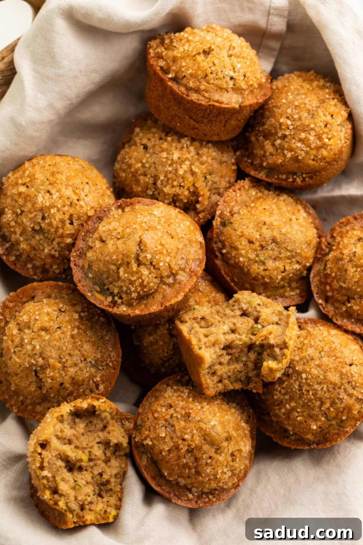 A linen-lined basket filled with warm, fluffy gluten-free zucchini muffins, ready to be enjoyed as a sweet treat.