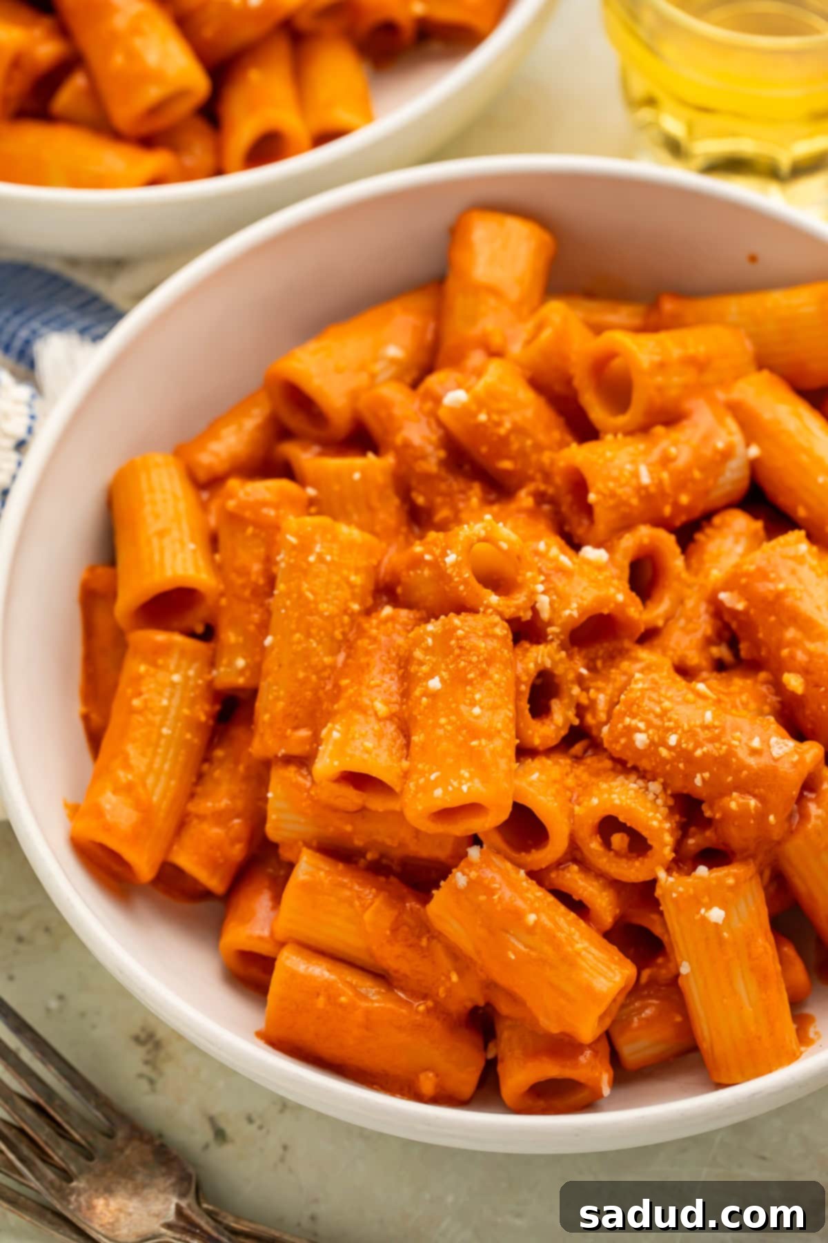 Close up of a white bowl of rigatoni pasta tossed with vegan vodka pasta sauce. 
