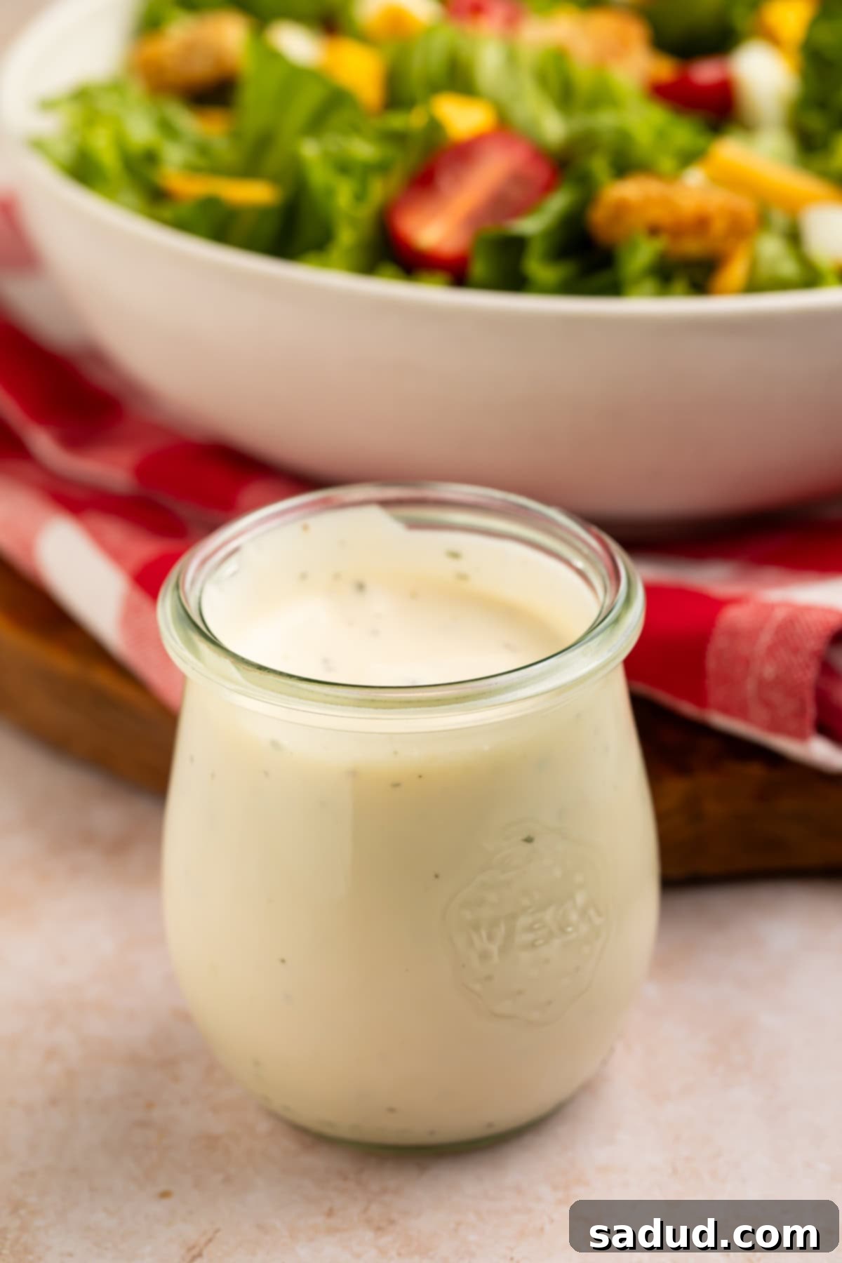 jar of ranch dressing with a tomato and lettuce salad just visible in the background. 