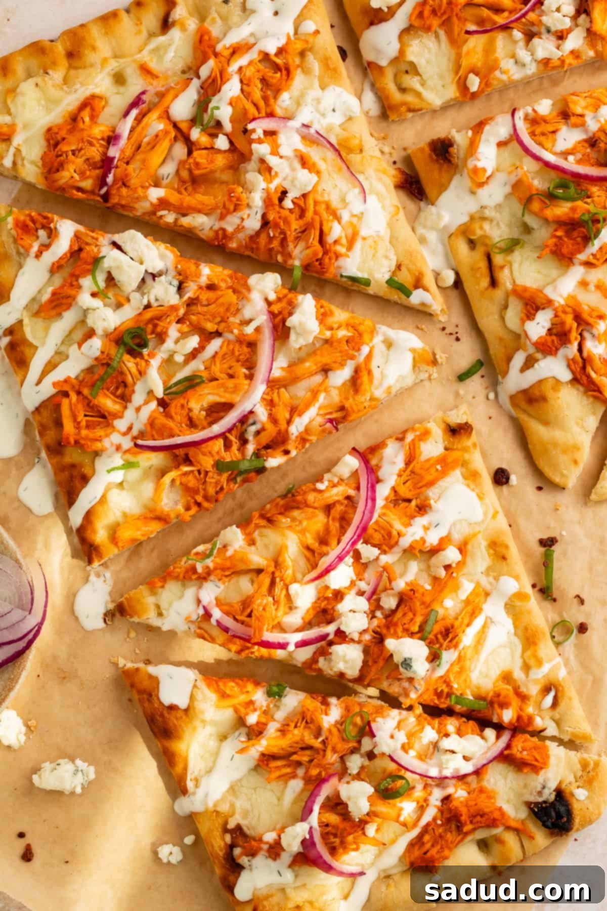 Zesty Buffalo Chicken Flatbread 2 Close-up of a perfectly baked Buffalo Chicken Flatbread, sliced into triangles, showcasing melted cheese, spicy chicken, and fresh toppings.