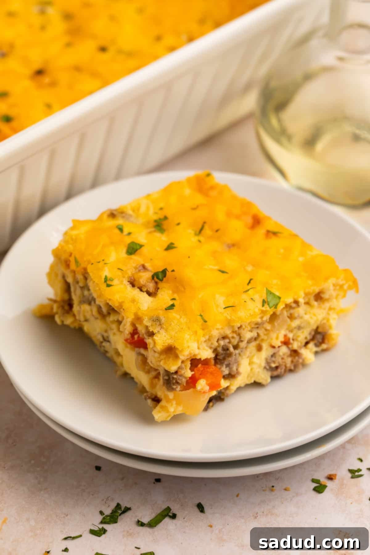 A perfectly portioned slice of high protein egg bake with cottage cheese, showcased on a white plate, with the full casserole dish visible in the soft-focus background, ready for serving.