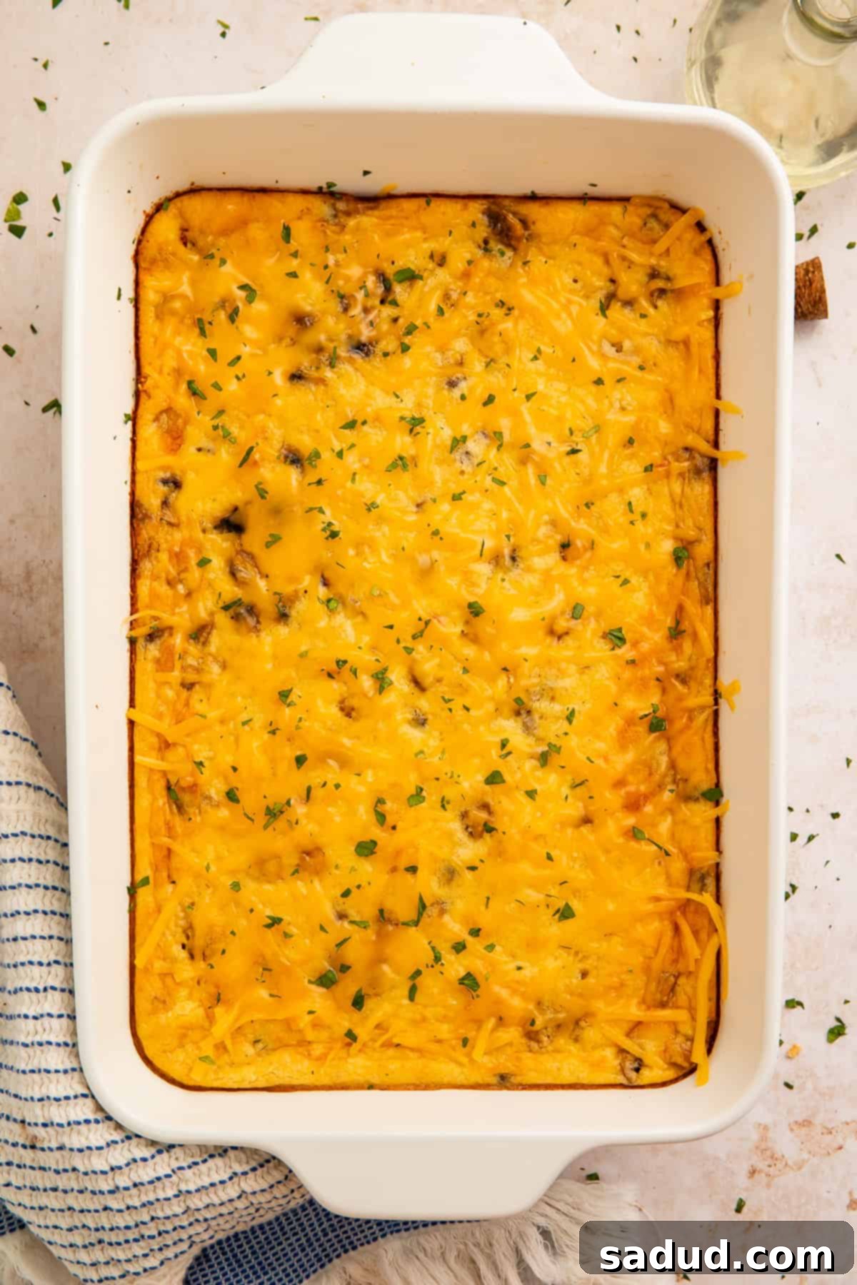 A close-up, top-down view of the high protein egg bake, highlighting the golden-brown melted cheese topping and the colorful mix of sausage and vegetables beneath, straight from the oven.