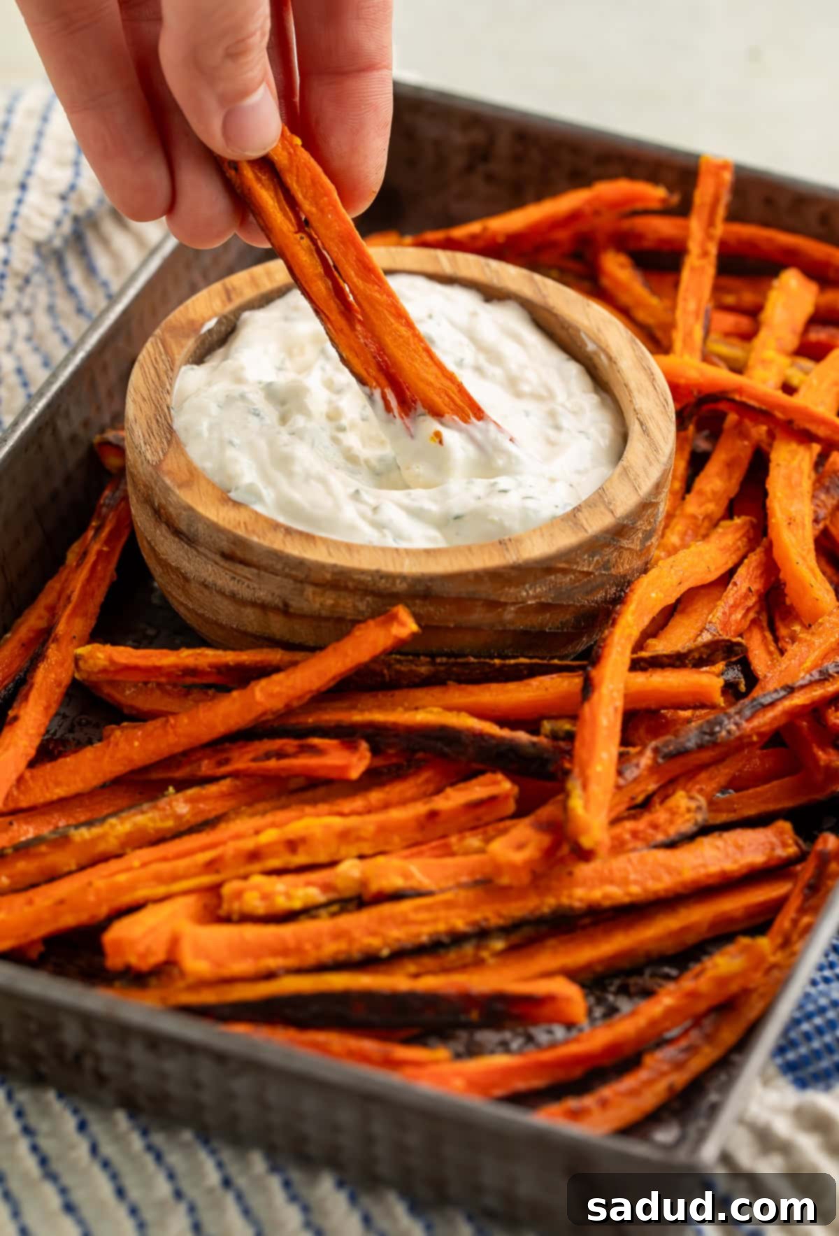 Crispy Carrot Fries 2 Carrot fry from a tray of them being dipped into a wooden bowl of creamy dip.