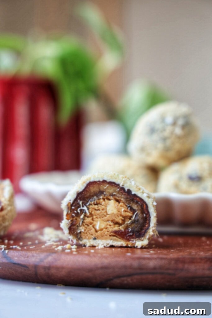 A stuffed date cut in half on a plate, showcasing the creamy hazelnut filling and white chocolate coconut coating.