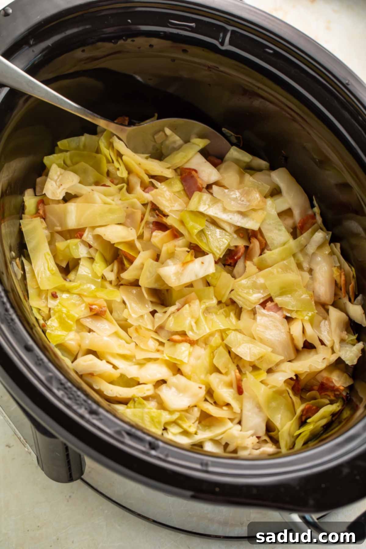 Tender Slow Cooker Cabbage 3 Close-up of Crockpot cabbage simmering in a slow cooker, showing the tender bacon and vegetables.