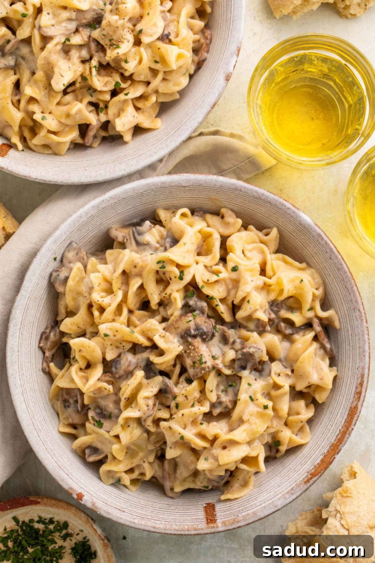 A large bowl filled with creamy mushroom stroganoff, garnished with fresh parsley, served on a rustic wooden table alongside a glass of white wine.